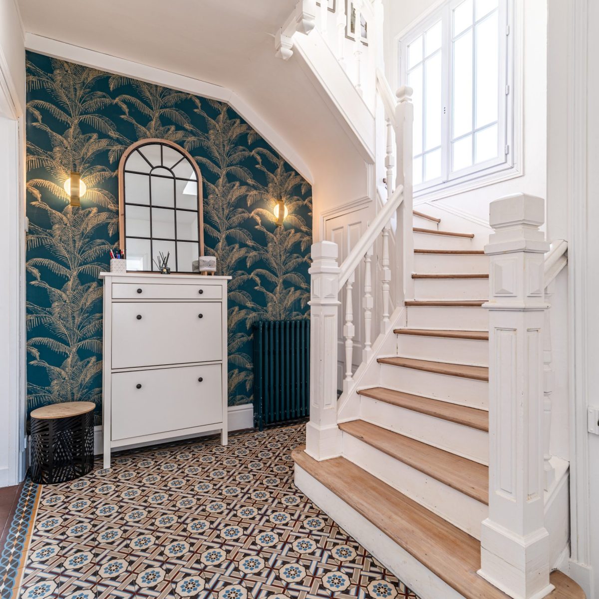 Carrelage en carreaux de ciment d'origine et escalier en bois rénové avec papier peint moderne et coloré