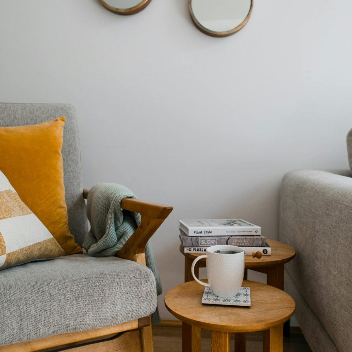 Fauteuil avec coussins, plaid, bout de canapé, café, miroir rond.